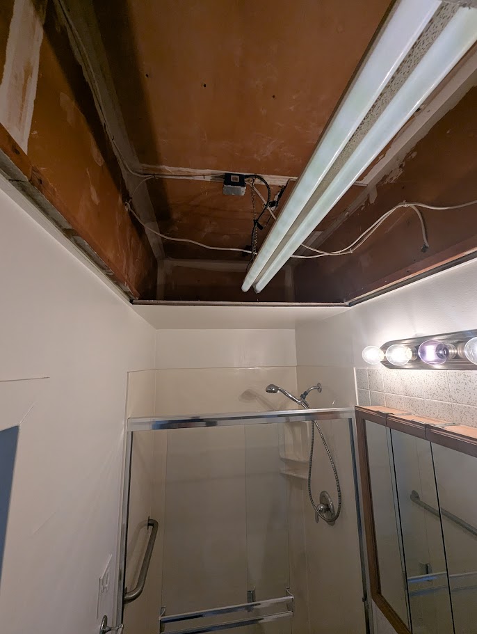 Bathroom drop ceiling with exposed wiring and open framing — a must-fix before any cosmetic work